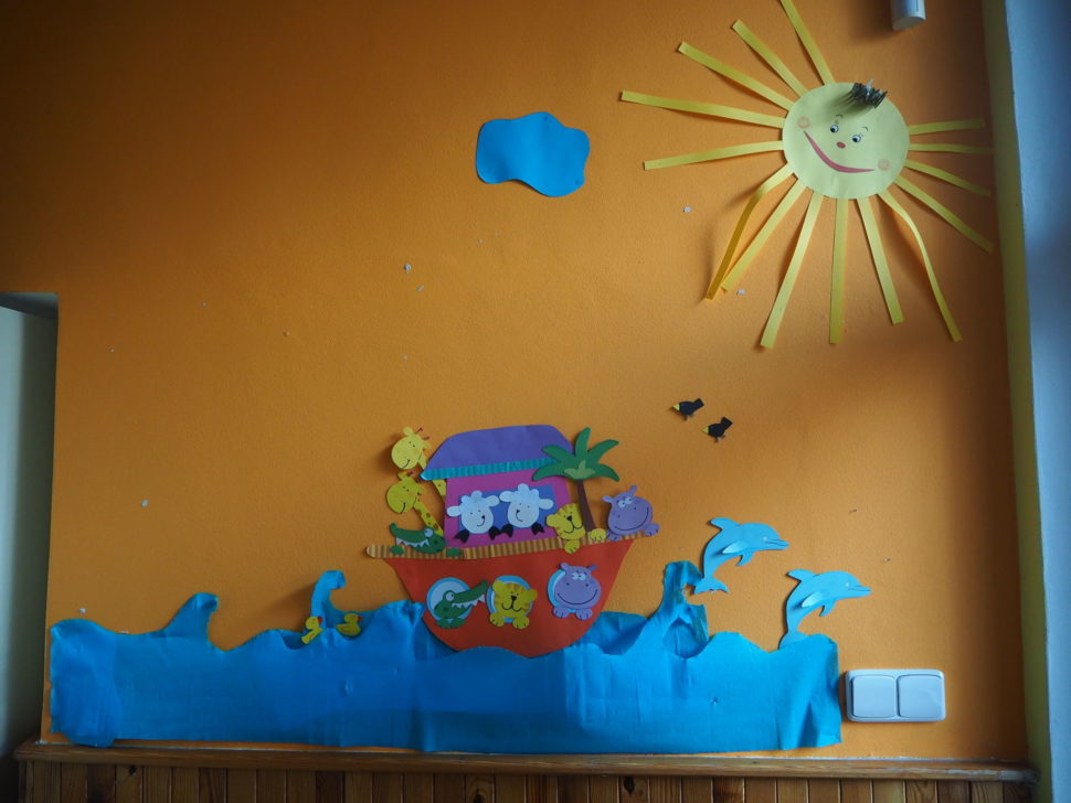 U dveří tělocvičny je na stěně umístěna loď se zvířaty a sluncem